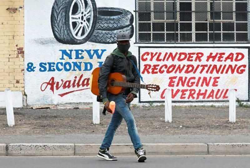 A busker wearing a face mask to prevent the spread of the coronavirus walks in the streets in Cape Town. (Photo by Gallo Images/Nardus Engelbrecht)